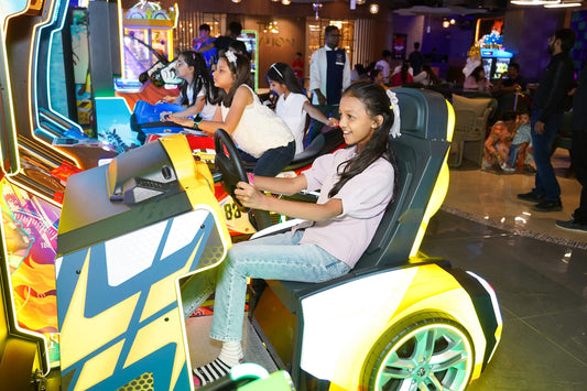 Girls enjoying colorful arcade racing games in a lively amusement zone at Boombastic Sector 62 Gurgaon Christmas Carnival