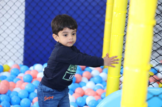 Toddler exploring colorful ball pit with protective yellow poles and netting in indoor play area at M3M Urbana Mall Sector 67 Gurgaon