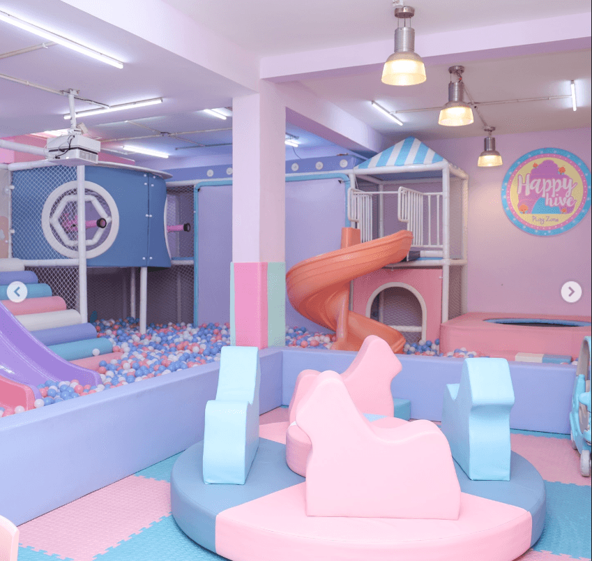 A colorful indoor playground with slides, ball pits, and soft play structures for children.