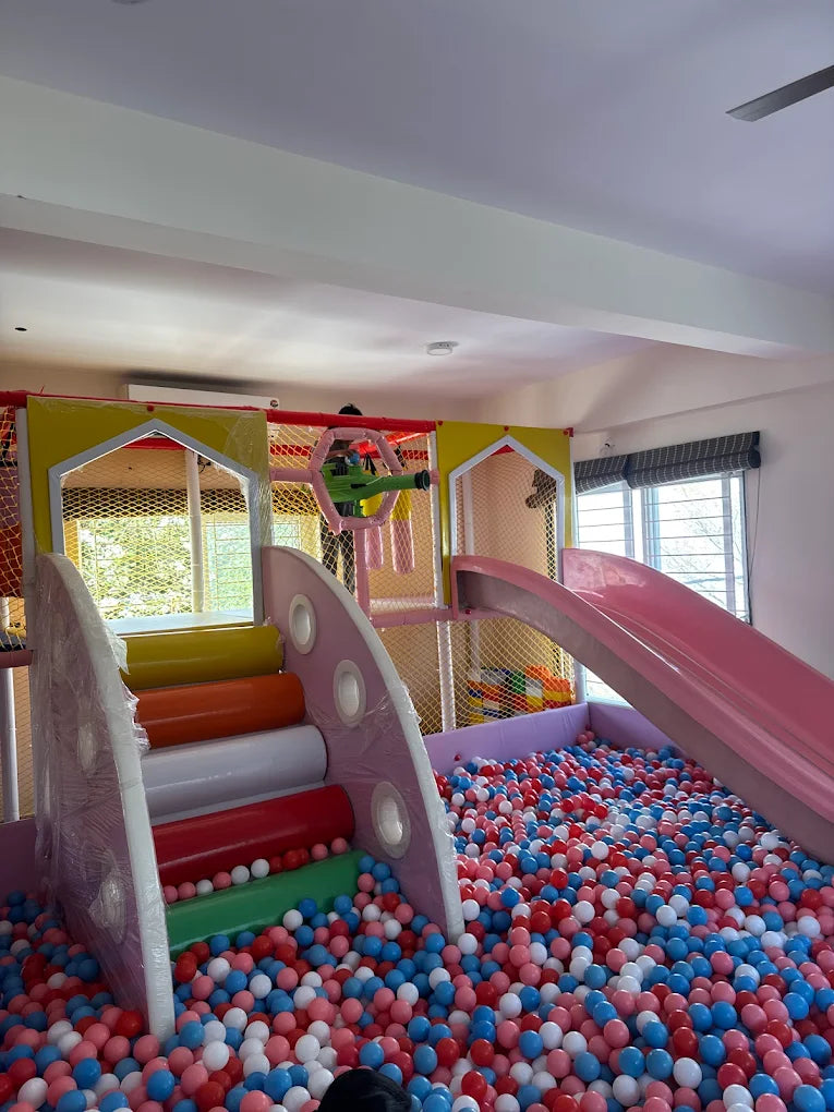 Children play in a colorful ball pit with slides and climbing structures.