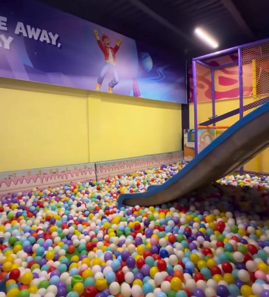 A ball pit filled with colorful balls and a slide in a children's play area.