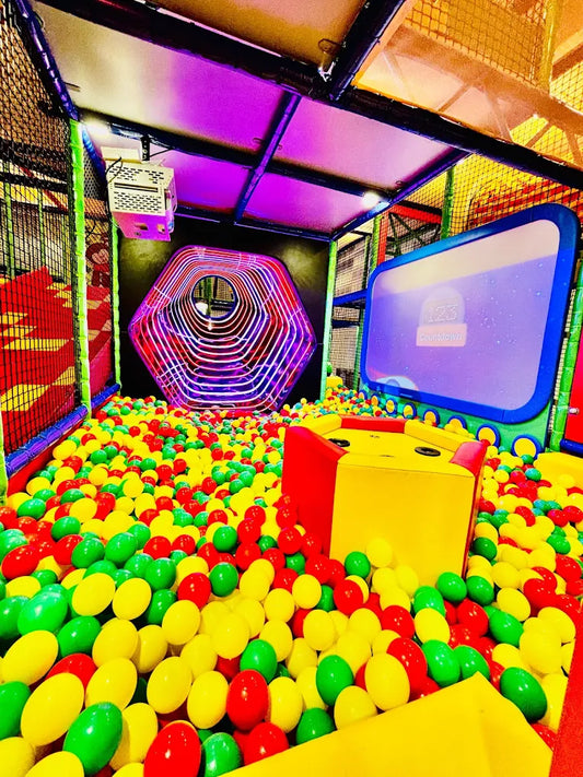 A colorful ball pit with a hexagonal tunnel and a digital countdown screen, likely in a children's play area.