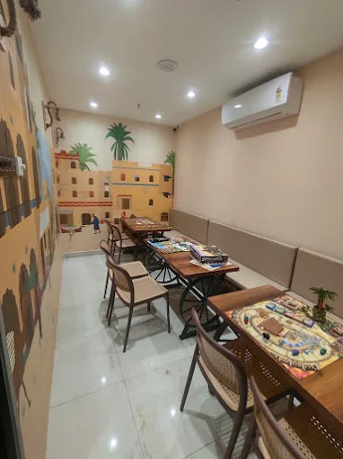 A game room with tables set up for board games, featuring a desert-themed mural.
