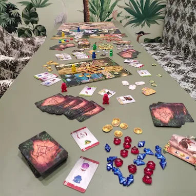 Board game setup on a table with colorful pieces against a decorative wall.