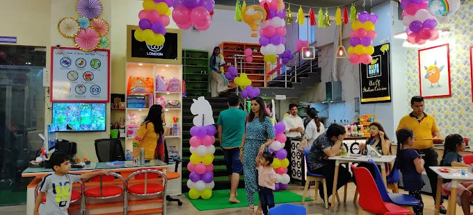 Indoor celebration with colorful balloon columns and families engaging in activities at House of Giggles Delhi session
