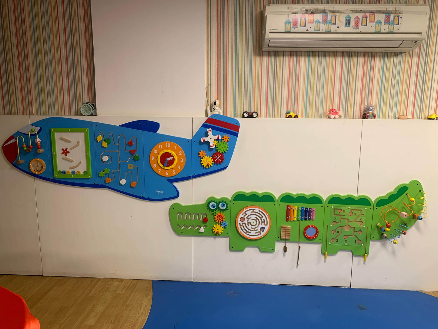 Wall-mounted interactive activity panels shaped like a blue airplane and green crocodile in kids playroom area