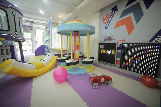 Children's playroom with colorful equipment, toys, and a large LED screen.
