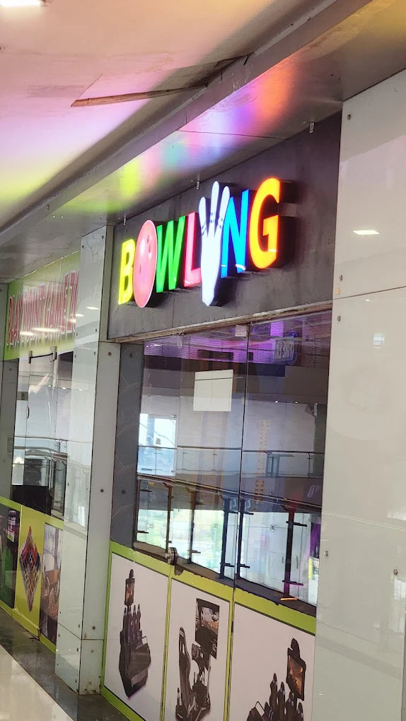 A colorful "BOWLING" sign illuminates a bowling alley entrance.