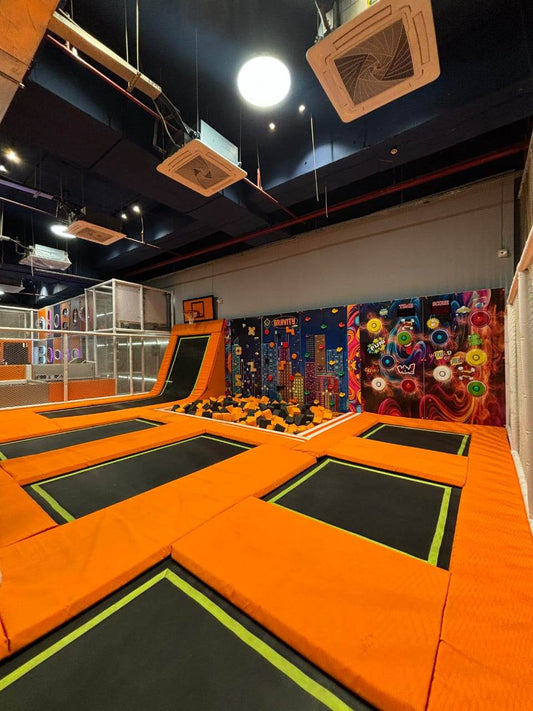 An indoor trampoline park with multiple interconnected trampolines and a foam pit, designed for children's active play.