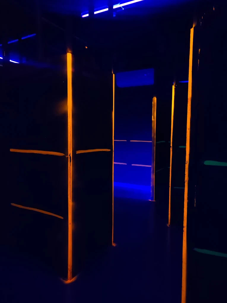 Dark indoor laser tag arena with glowing orange and blue lights.