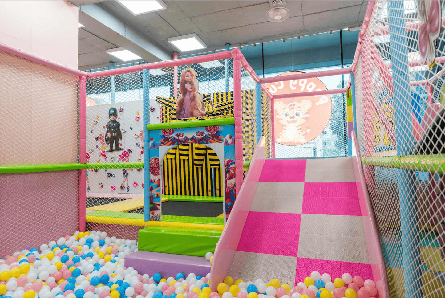 A colorful indoor playground with a ball pit, slide, and cartoon characters for children.