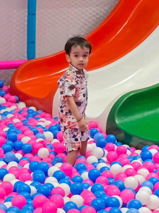 Child standing in colorful pink, blue, and white ball pit near tricolor slide at Pitaara Fun Zone Mahagun Mall Vaishali Ghaziabad