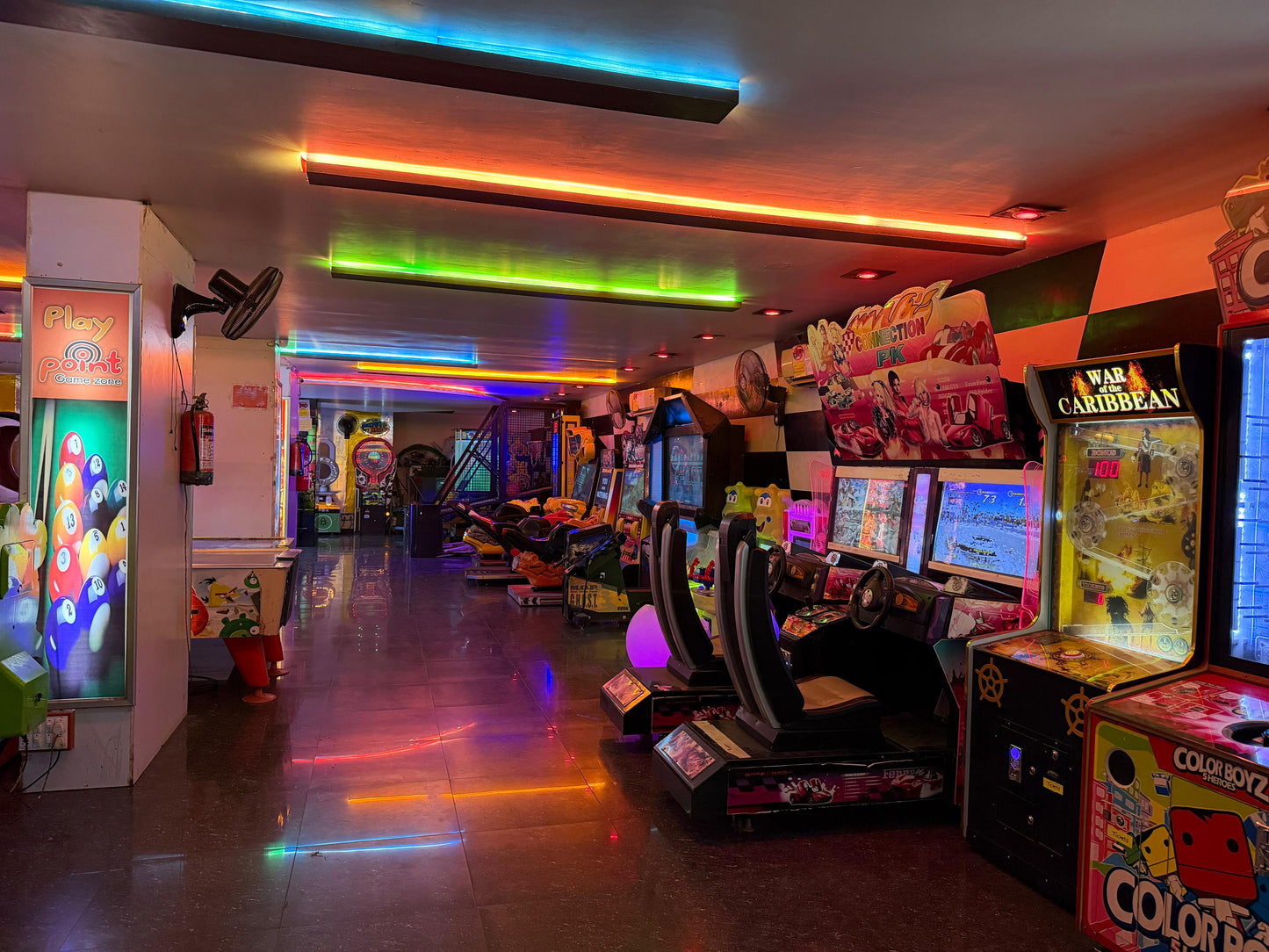 An arcade with rows of colorful game machines and neon lights.