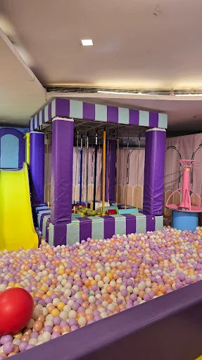 A colorful ball pit with a yellow slide and a purple and teal play structure.