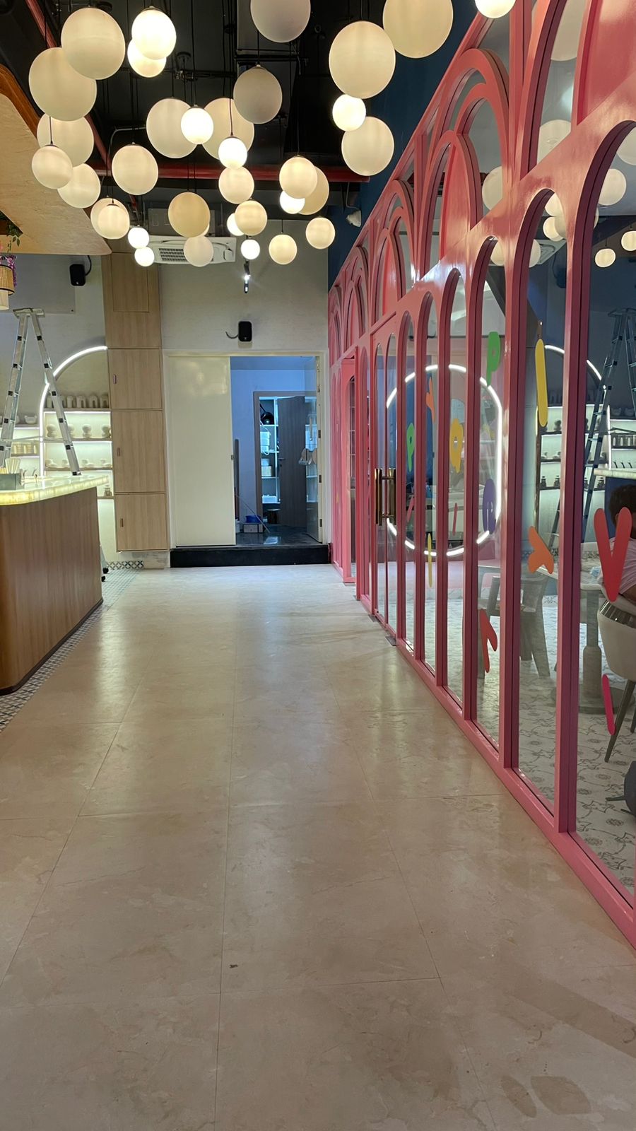 A modern interior with a pink arched glass wall and a ceiling filled with spherical lights.