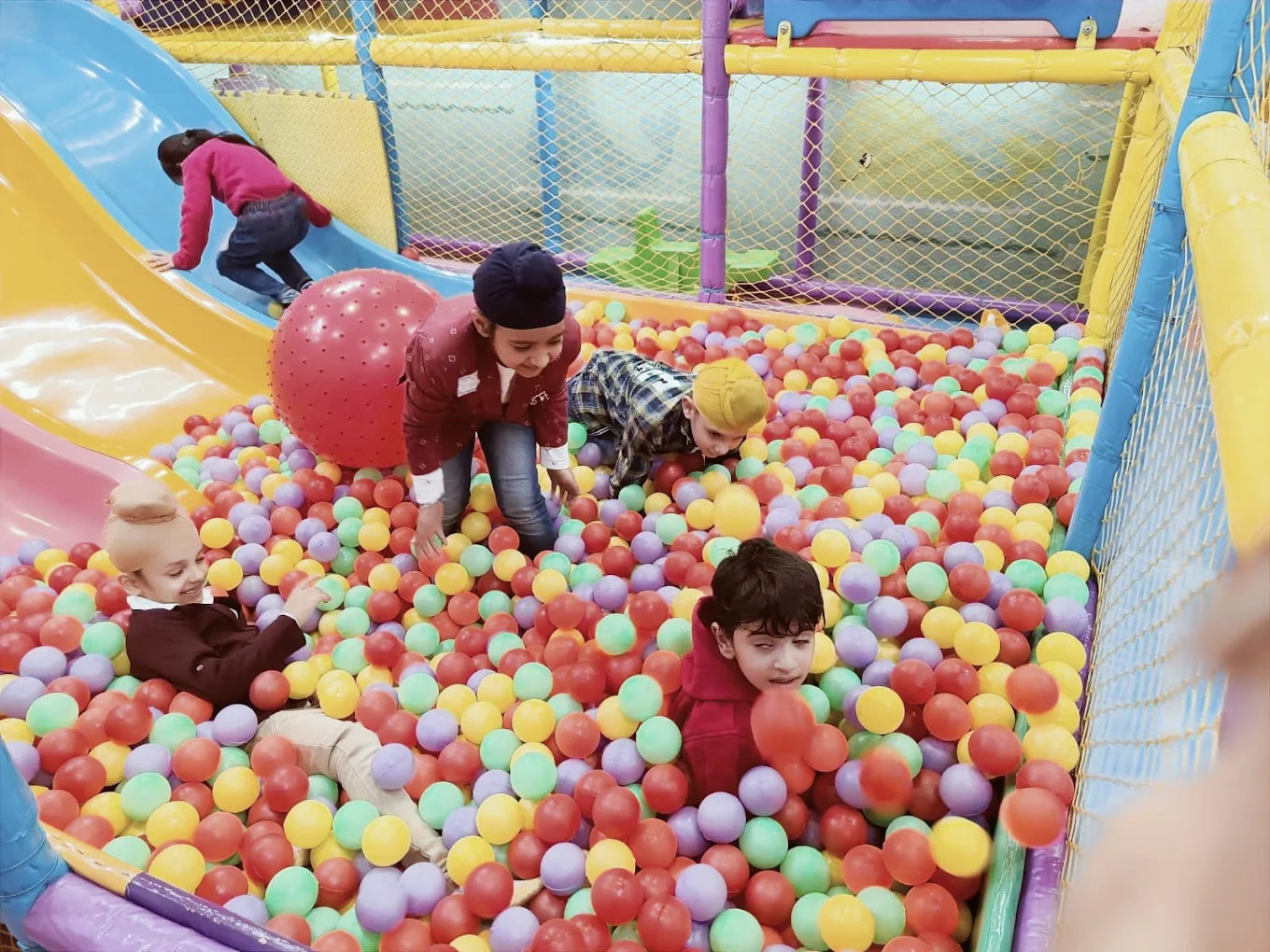 Children play in a ball pit with a slide.