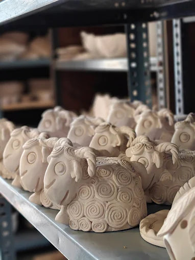 Row of ceramic animal figures on a shelf in a workshop setting