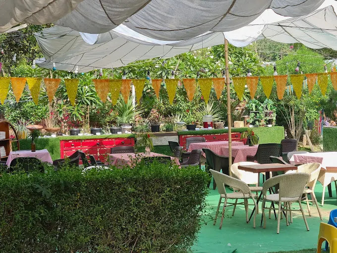 Outdoor event setup with tables, chairs, and colorful decorations in a garden.