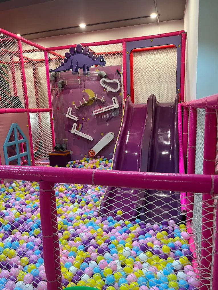 A colorful indoor playground with a ball pit and slides, designed for young children.