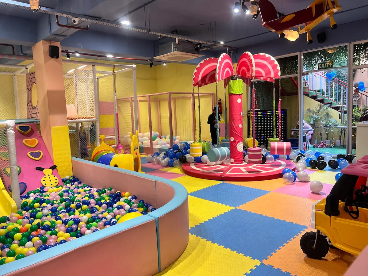 Bright indoor play space with ball pit, soft play structures, colorful flooring, and children exploring activities