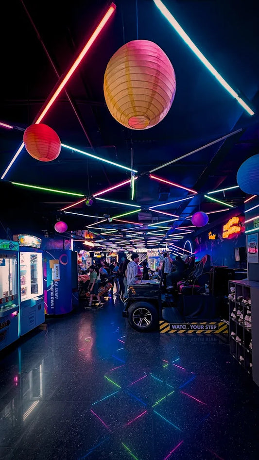 Indoor arcade with colorful neon lights and hanging lanterns illuminating game machines at Zoreko Play Zone Unity One Mall