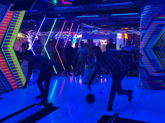 Indoor bowling alley with vibrant neon light walls and players in action at Zoreko Play Zone Rajouri Garden Delhi