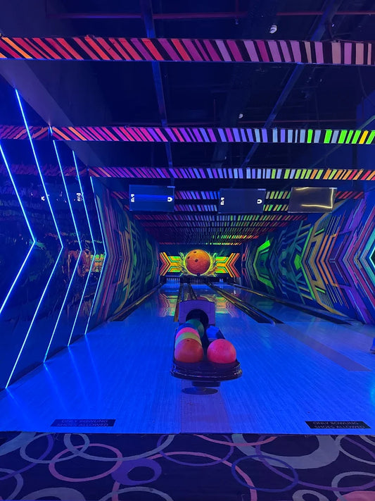 A neon-lit bowling alley with colorful lanes and bowling balls.