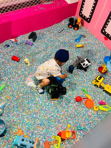 Child playing with toys on a colorful sandpit floor in a play area