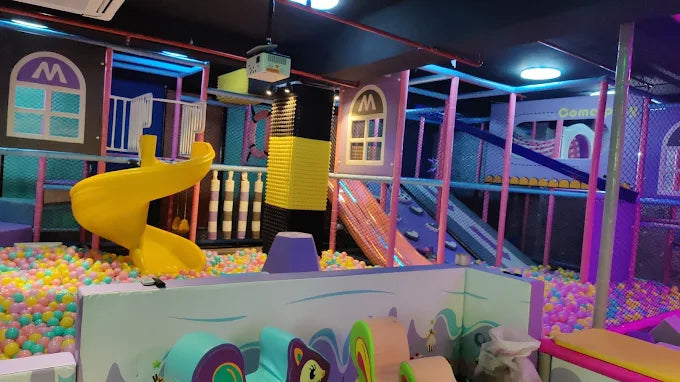 A colorful indoor playground with slides, ball pits, and climbing structures for children.