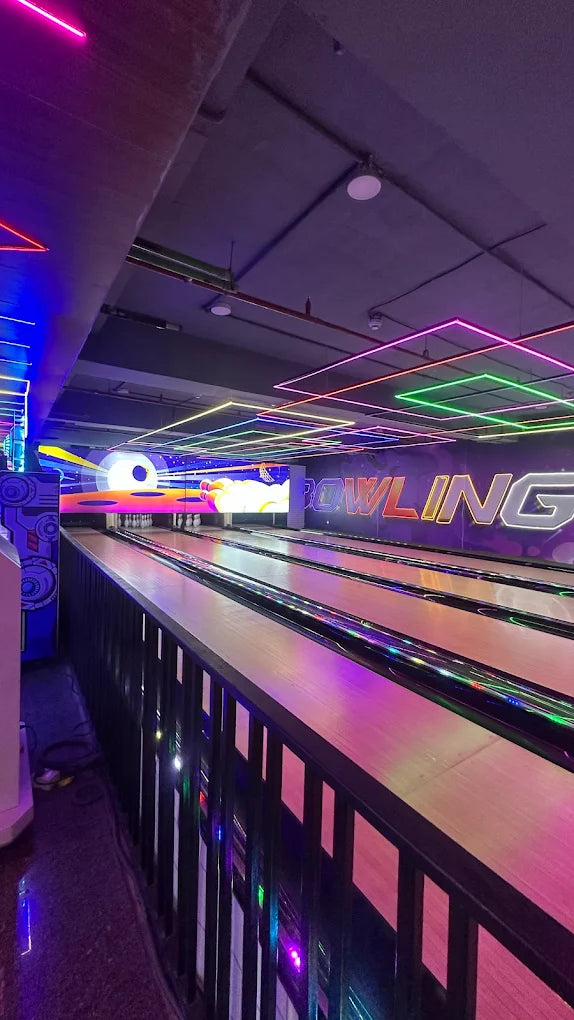 A bowling alley with neon lights and a colorful digital screen displaying the word "BOWLING."