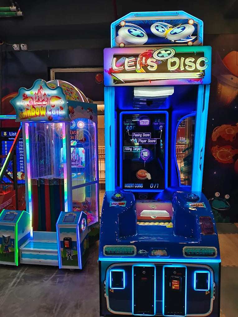 Two brightly lit arcade games, "Rainbow Castle" and "Let's Disc," stand in an arcade.