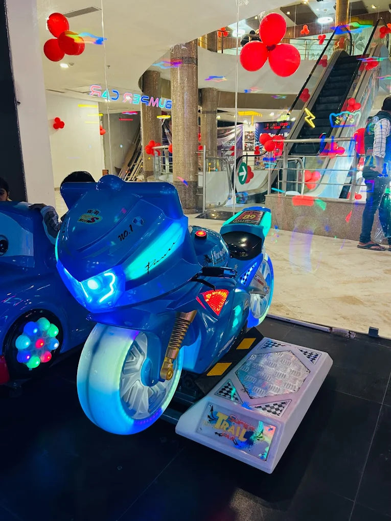 A blue toy motorcycle ride with neon lights in an arcade, with escalators in the background.