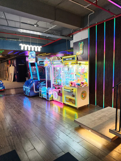 Arcade with claw machines and colorful lights.