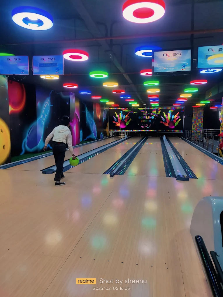 A person bowls in a brightly lit bowling alley with colorful lights and decorations.