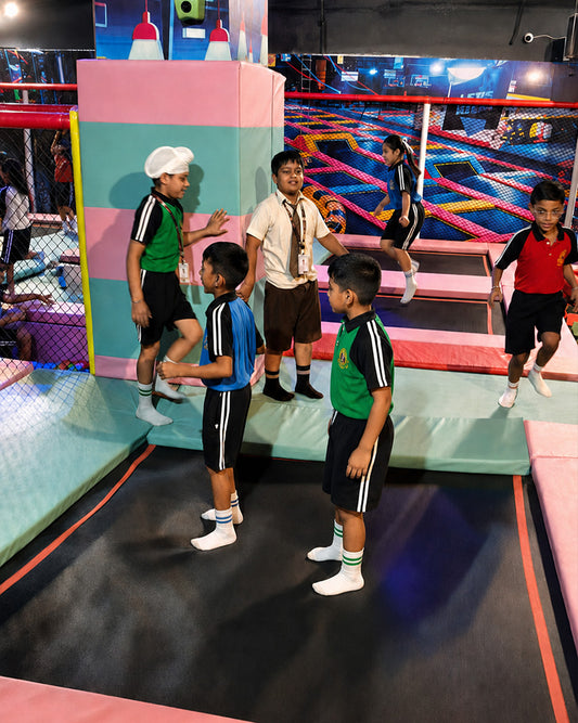 Children in school uniforms enjoy a trampoline park, jumping and playing together.