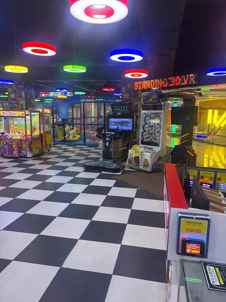 An indoor arcade with colorful lights, game machines, and a checkered floor.