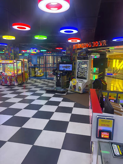 An indoor arcade with colorful lights, game machines, and a checkered floor.