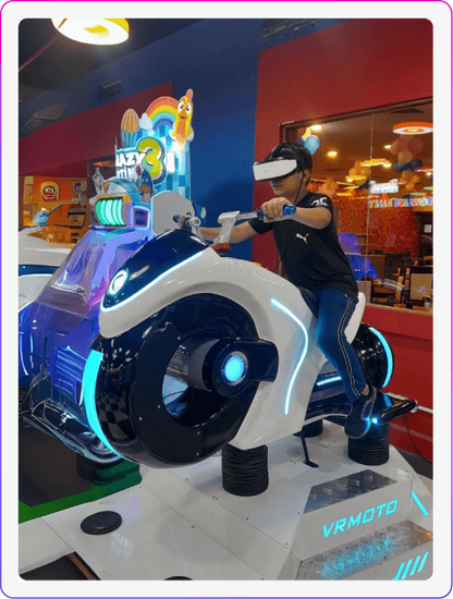 A young person plays a VR motorcycle game in an arcade. The game features a futuristic white motorcycle with blue lights.