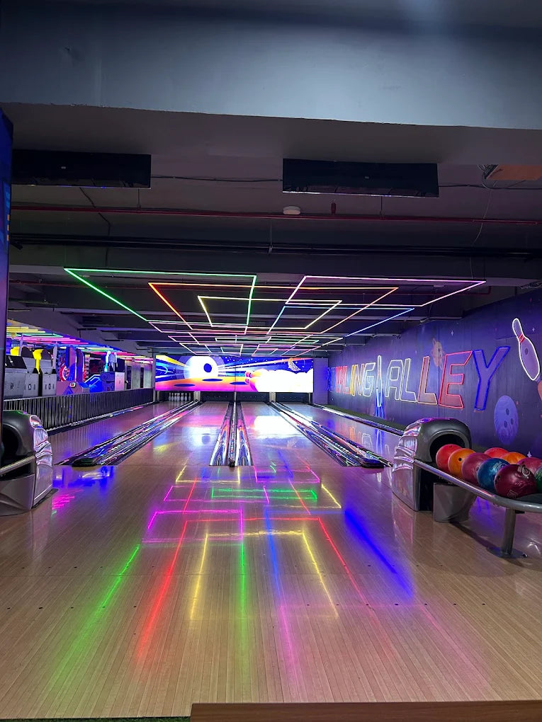 A bowling alley with neon lights reflecting on the lanes.