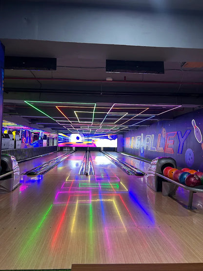 A bowling alley with neon lights reflecting on the lanes.