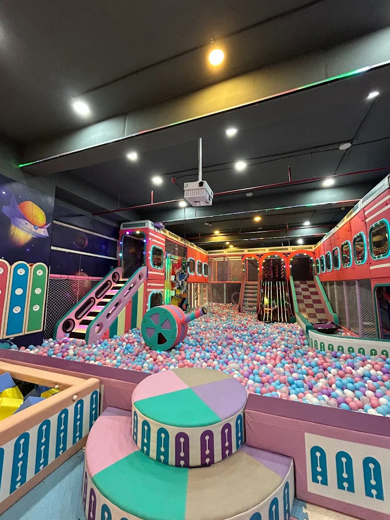 A colorful indoor playground filled with balls, slides, and climbing structures for children.