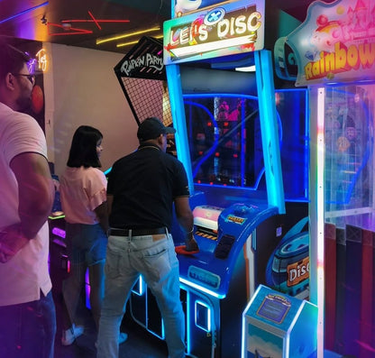 Adults play an arcade game called "Let's Disc" in a brightly lit entertainment center.