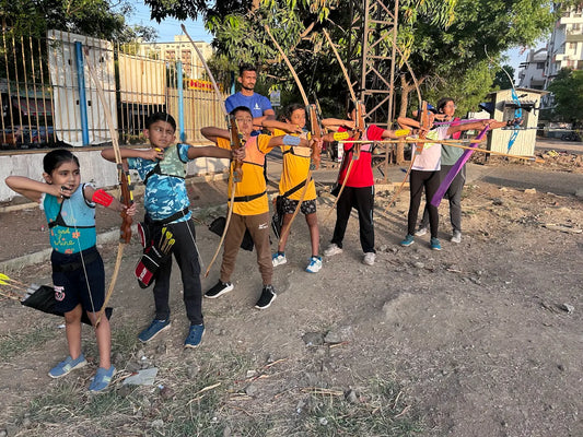 Children practice archery outdoors with bows and arrows.