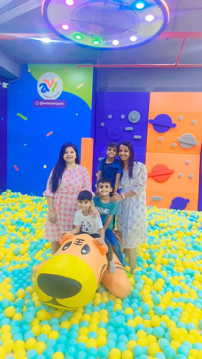 A family poses in a ball pit with a large inflatable tiger.
