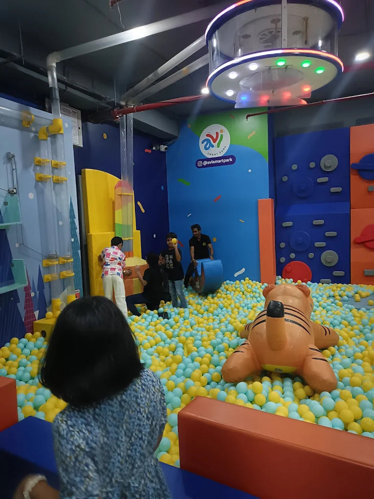 Children play in a ball pit with a tiger inflatable at an indoor amusement park.
