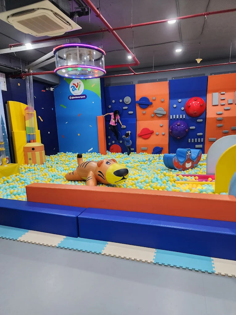 Children play in a ball pit with a tiger inflatable and a climbing wall.