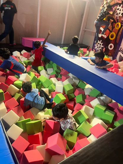 Children playing in a colorful foam pit at an indoor playground.