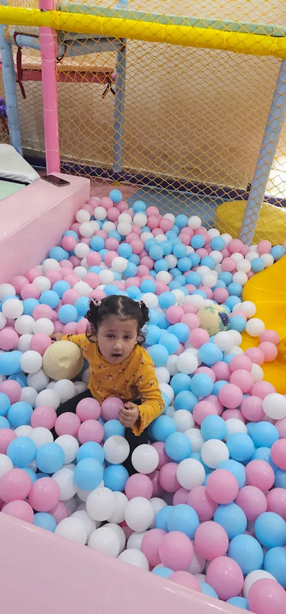 Child playing in a ball pit with colorful balls in an indoor playground.