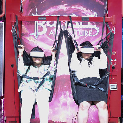 Two young people wearing VR headsets sit in suspended seats, ready for a virtual reality adventure.