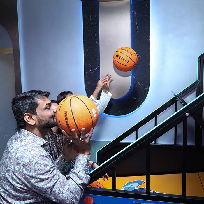 A man holds a basketball to his face while another person throws a basketball in a game.